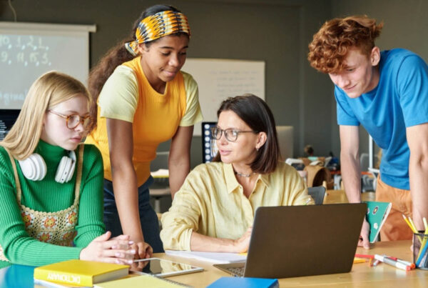 Instructor teaching three students about the digital SAT changes on a laptop